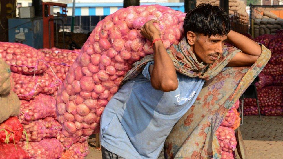 A labourer carries a sack of onions at a wholesale vegetable market on the outskirts of Amritsar on September 19, 2019.