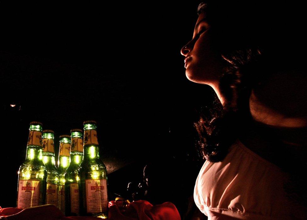 Indian models gestures as she holds bottles of Kingfisher beer during the launch of commemorative packs of 'Indian October Fest' beer bottles