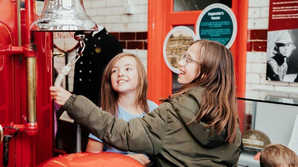 Young girls ringing a fire engine bell