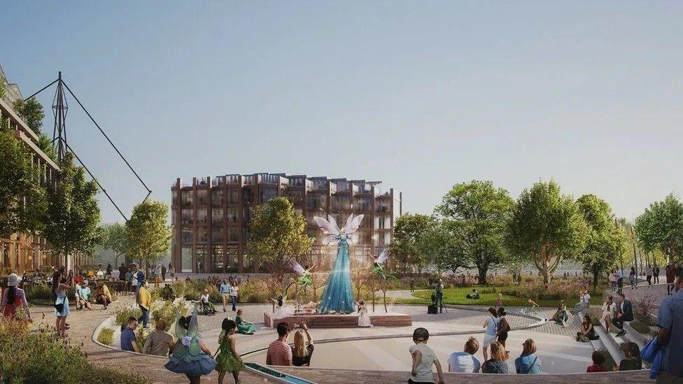 An artist's impression of the new Oxpens site. A sculpture of what appears to be fairies is at the centre of a busy square. Modern looking buildings are behind.