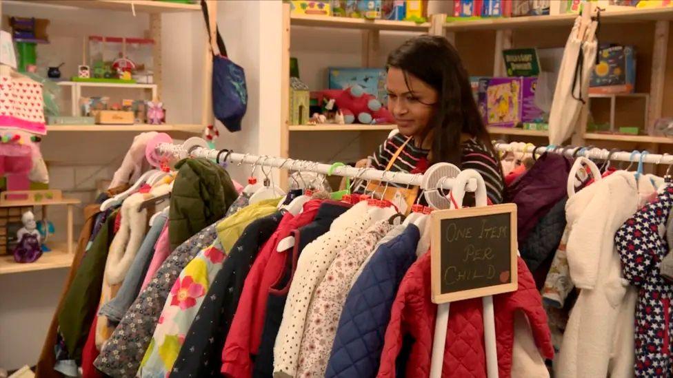 A woman looks through a rail of clothes at the charity's hub 