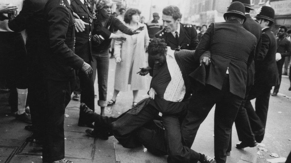 A black man is arrested by two white police officers in Brixton