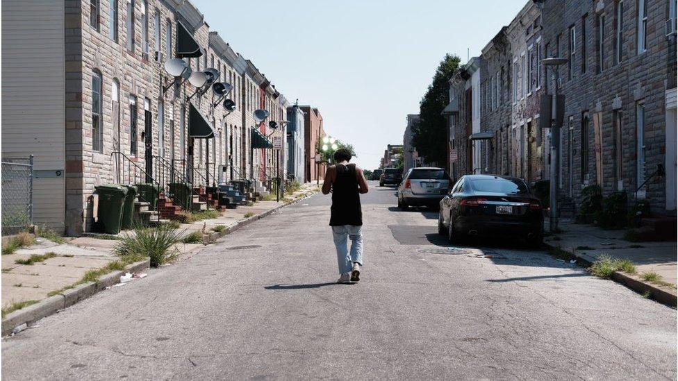 A man walks down a Baltimore street near where a person was recently murdered on July 28, 2019 in Baltimore, Maryland