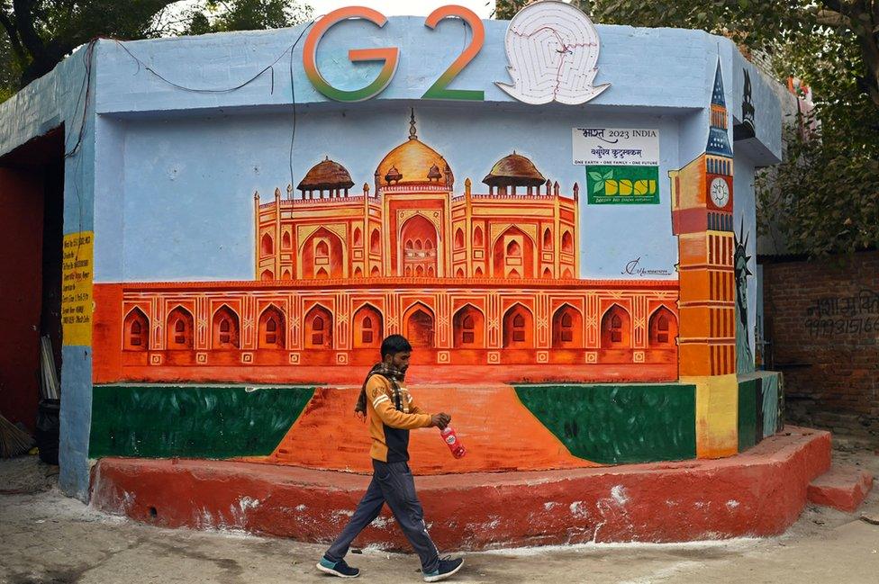 A man walks past a wall mural of Humayun's tomb under the logo of G-20 Summit, in New Delhi on January 4, 2023.