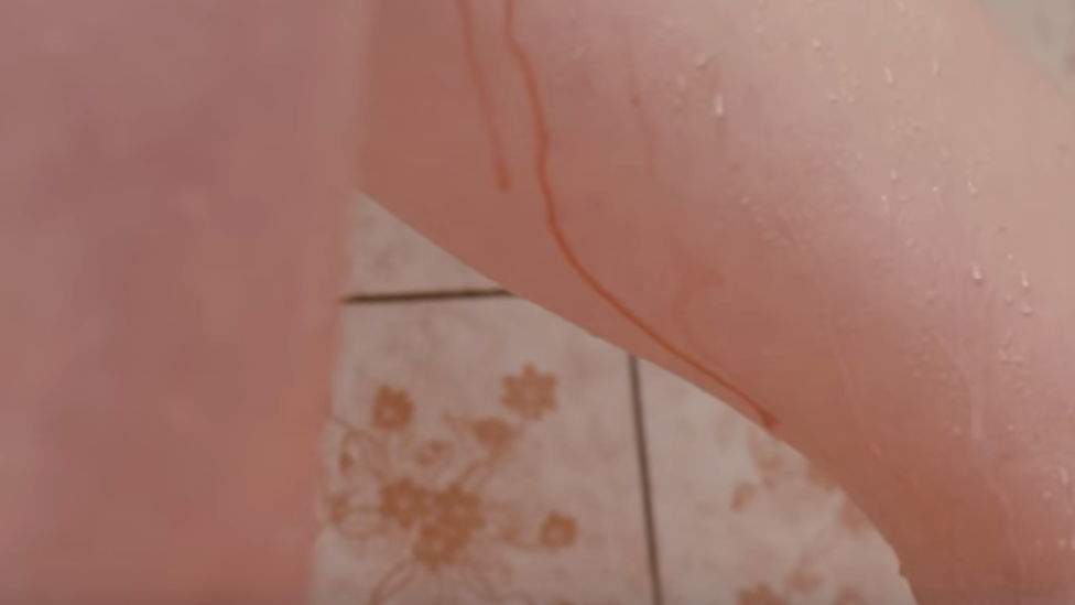 Woman in the shower with blood on her thighs