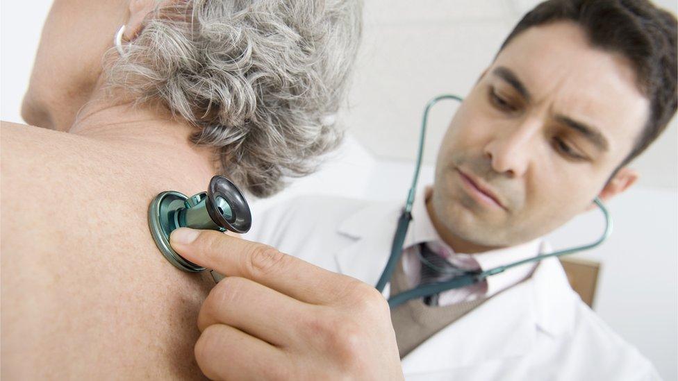 A GP listening to a woman's chest