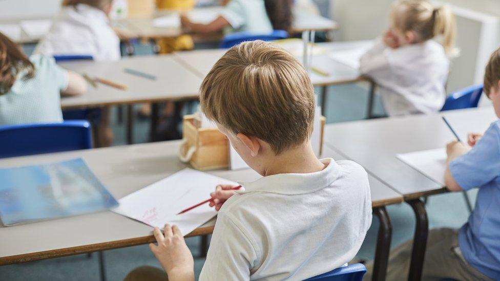 A boy at work as his desk in a school classroom