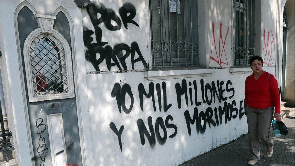 A woman walks in front of the Cristo Pobre Church whose facade walls were painted with messages against Pope Francis" visit in Santiago, Chile, 12 January 2018.