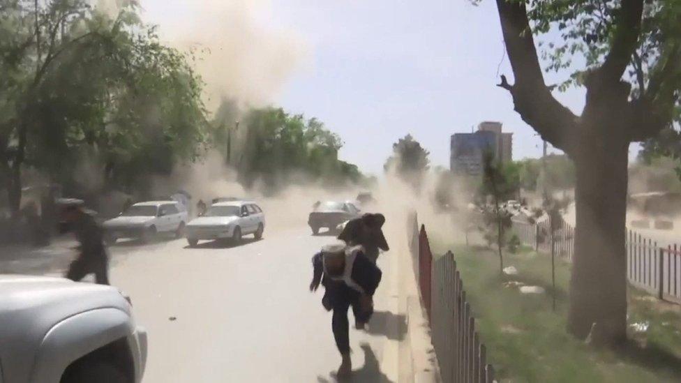 Three people flee clouds of dust at the site of the attacks