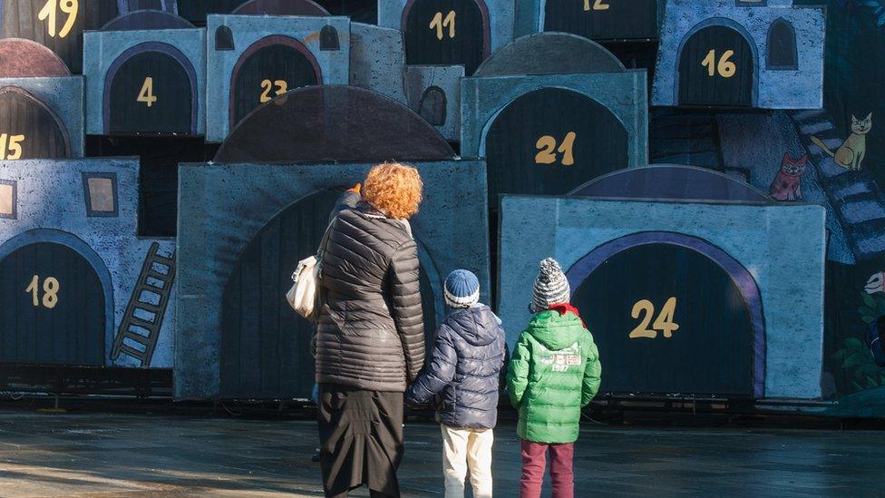 A woman and two children looking at a large advent calendar