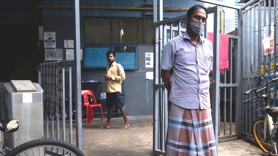 migrant workers wearing protective face masks can be seen in a factory-converted dormitory for migrant workers on April 20, 2020 in Singapore.