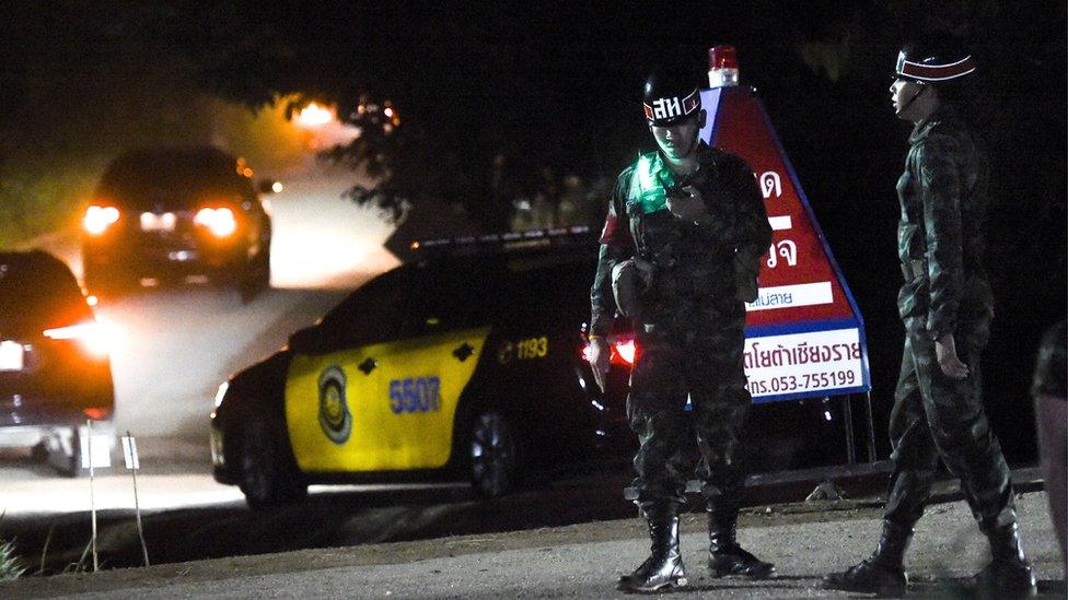 Military police secure the road as large convoy of official vehicles enter the Tham Luang cave area