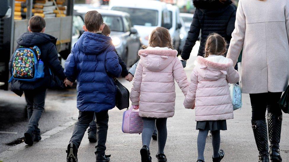 Four children and an adult walking