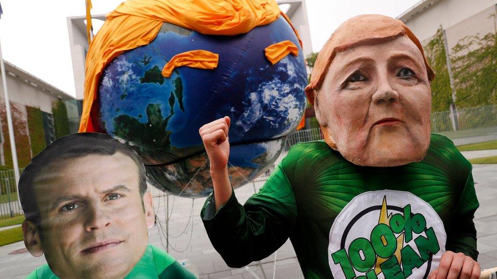 Two protestors wearing face masks of German Chancellor Angela Merkel (R) and French President Emmanuel Macron (L) demonstrate outside the German Chancellery ahead of the arrival of the European leaders in Berlin, Germany, 29 June 2017