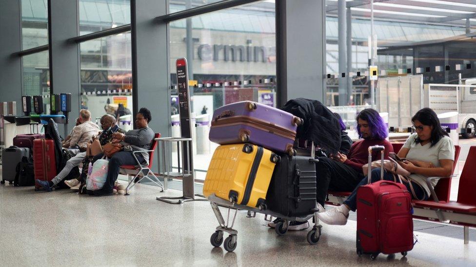 Travellers, whose flights are cancelled, sit at Heathrow Airport, as Britain's National Air Traffic Service (Nats) restricts UK air traffic due to a technical issue causing delays in London