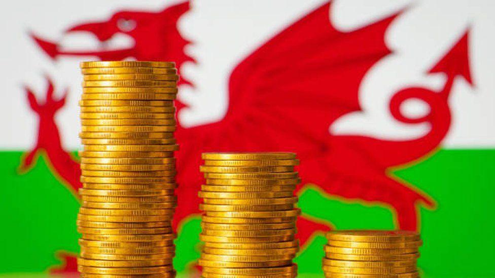 Welsh flag in the background with gold coins in front.