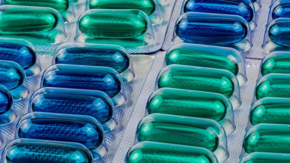 Blue and green soft gel painkiller capsules in a blister pack