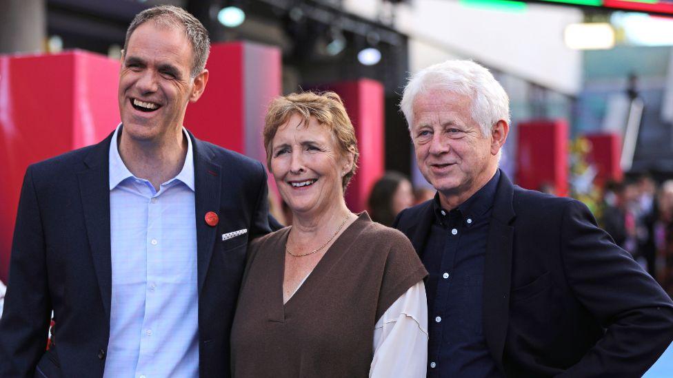 Simon Otto, wearing a navy suit, Fiona Shaw, wearing a brown vest and cream shirt, and Richard Curtis, also in a navy suit, attend the Headline Gala screening of That Christmas during the 68th BFI London Film Festival in October