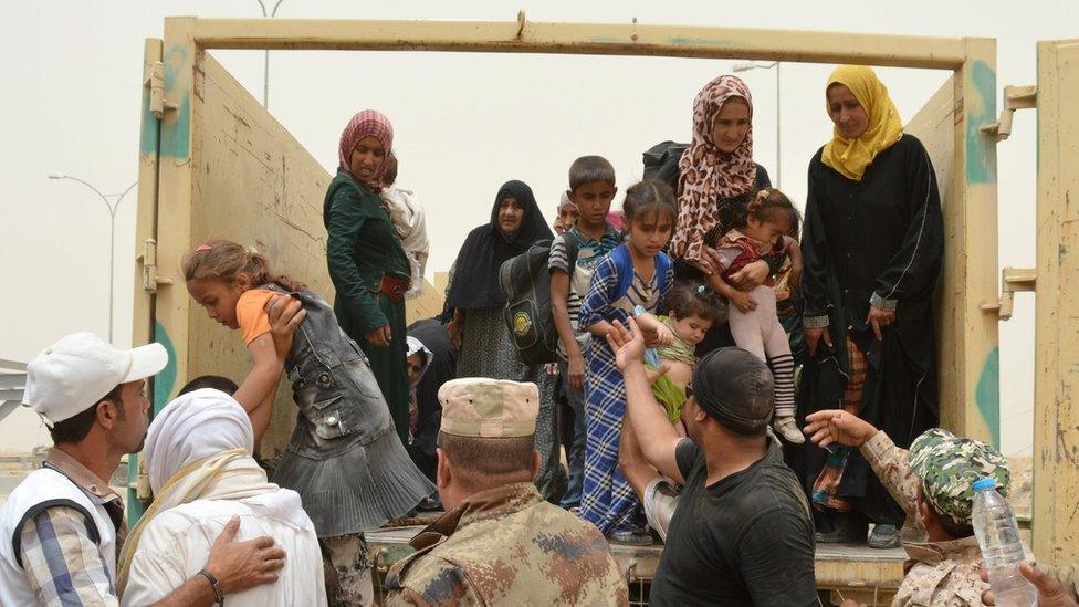 Iraqi soldiers help civilians who have fled Falluja during a dust storm on the outskirts of the city, Iraq, 18 June, 2016