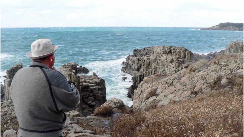 Former police officer Yukio Shige stands near the cliffs of Tojinbo, looking out to sea with a pair of binocular in hand. Fukui prefecture, northern Japan, 23 December 2008.