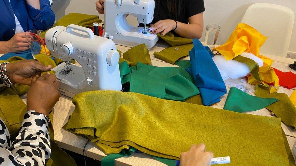 Women at a table with sewing machines and fabric