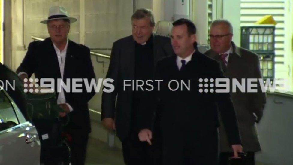 Cardinal Pell (second from left) arrives in Sydney, accompanied by police and private security staff