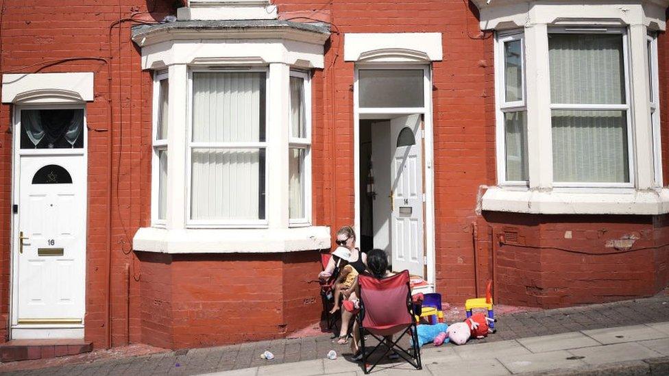 Family sat on chairs outside a house