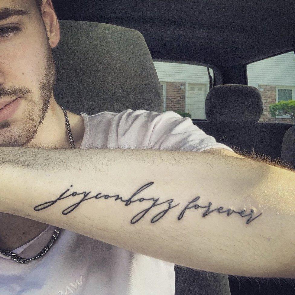 A man showing off his tattoo. It reads 'joyconboyz forever' written in italic font.