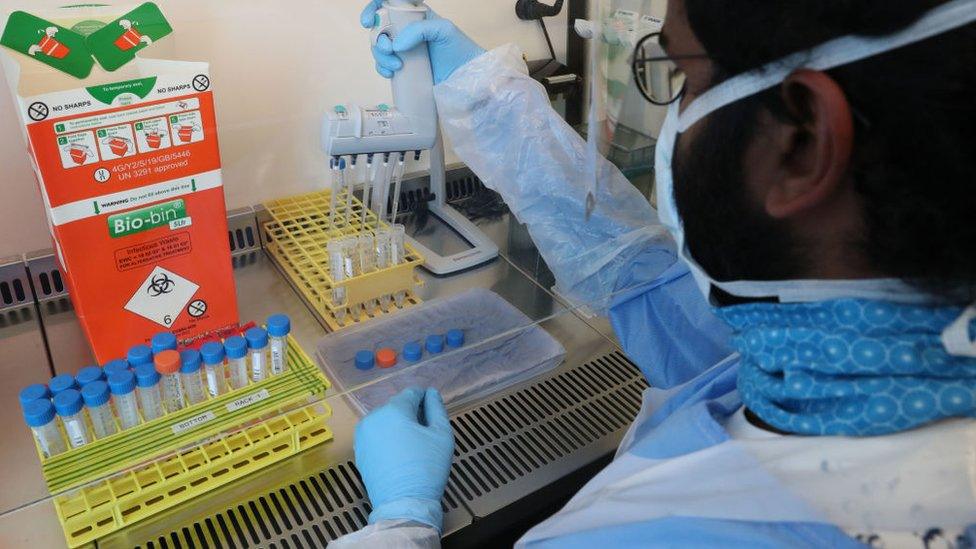 Technicians carry out a sample transfer during the opening of the new Covid-19 testing lab at Queen Elizabeth University Hospital