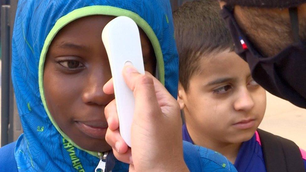 A child's temperature is taken on arrival at schools in Seine Saint Denis