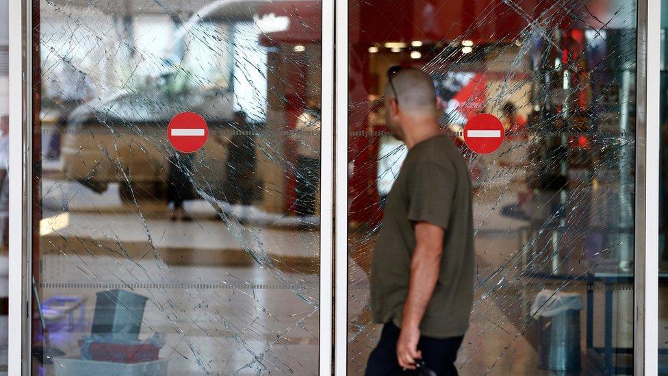 A person walks in front of broken window gates after multiple attacks at Ataturk international airport in Istanbul, Turkey, on 29 June