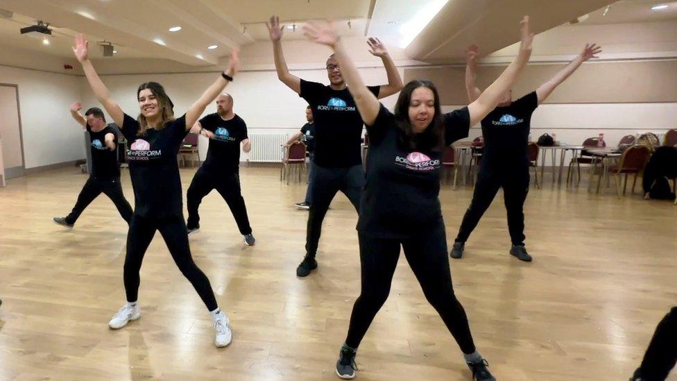 Women in black outfits dancing with arms upwards