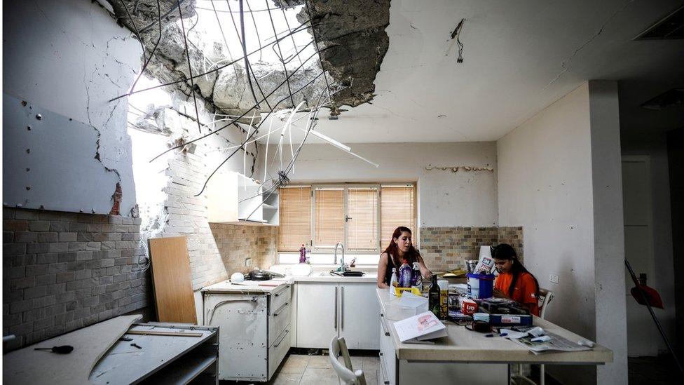 Members of the Vaizel family sit in the kitchen of their house, which was damaged after it was hit by a rocket launched from the Gaza Strip, in Ashkelon, Israel (20 May 2021)