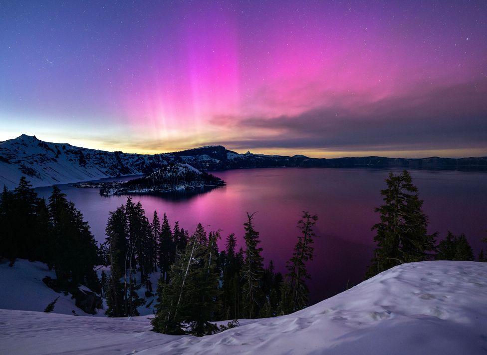 The Northern Lights (aurora borealis), glowing on the horizon, over Crater Lake at Crater Lake National Park in Oregon,  11 May 2024