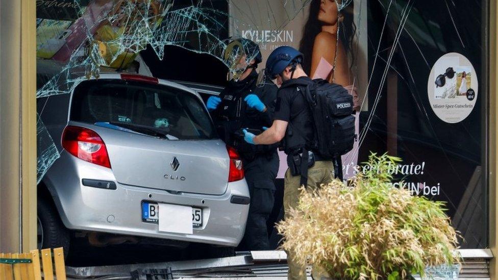 Police officers stand next to a car that crashed into a group of people and ended up in a storefront near Breitscheidplatz in Berlin, Germany, June 8,