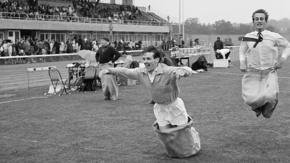 Three men take part in a sack race