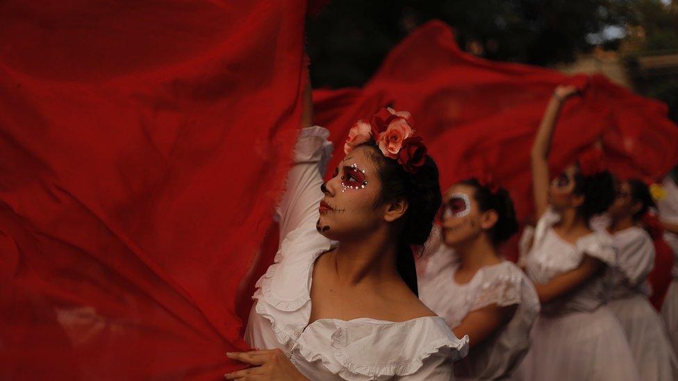 Women, dressed up, carry red fabric