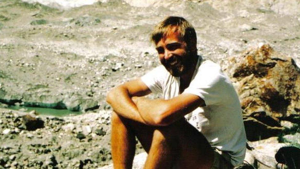 A photo of a younger Mike Thexton sitting on a rock on the Lobsang Spire mountain