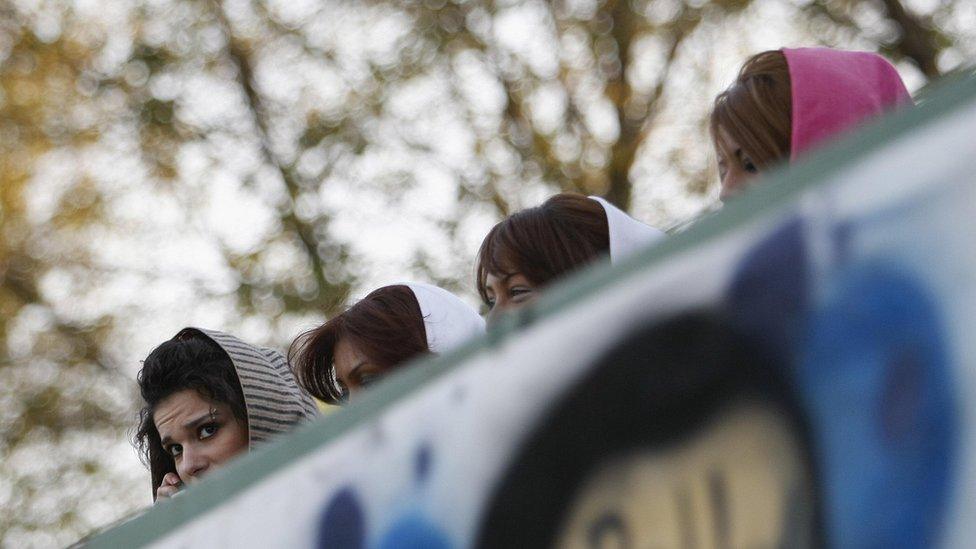 Iranian women in veils watch a football match from a nearby shopping mall in Tehran on 10 October 2008