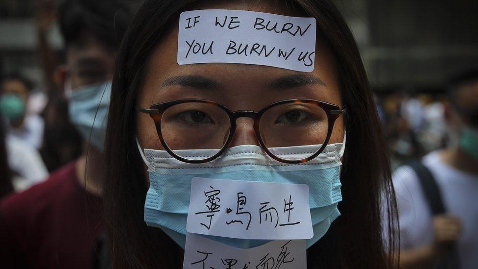 Masked protesters march in the street as they take part in a rally held to show opposition to an anti-mask law meant to deter anti-government protesters,