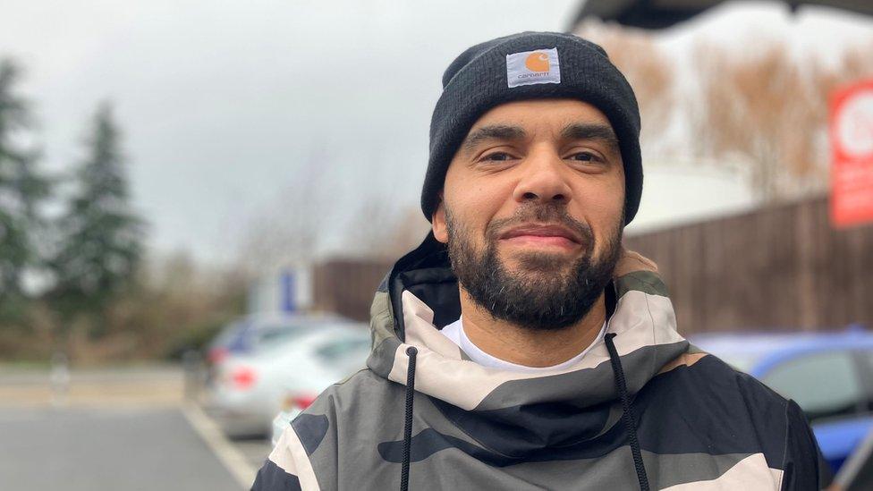 Man in a camouflage jacket and black Carhartt hat