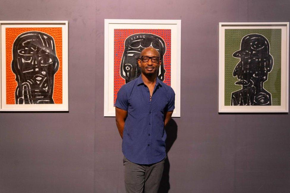 Ayoola Gbolahan, an artist represented by Kanbi projects, poses for a picture in front of his artwork.