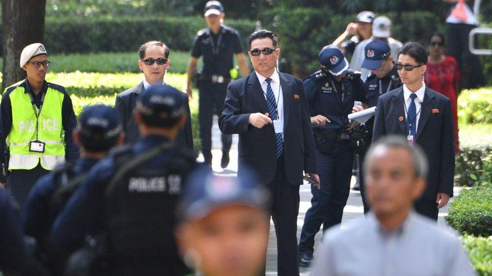 North Korean security personnel (C, wearing sunglasses) keep watch outside the St. Regis hotel, where North Korean leader Kim Jong Un is staying