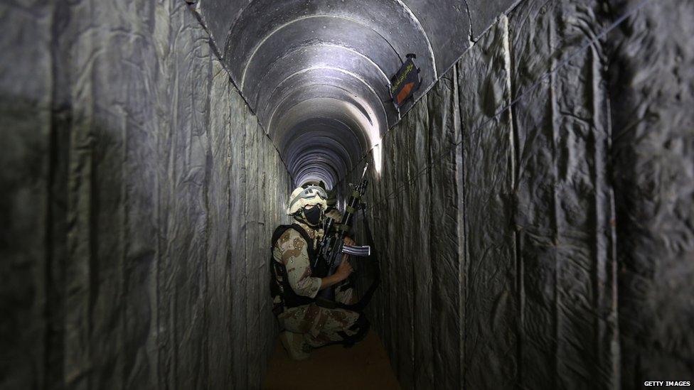 Al Quds Brigade member crouches in a tunnel