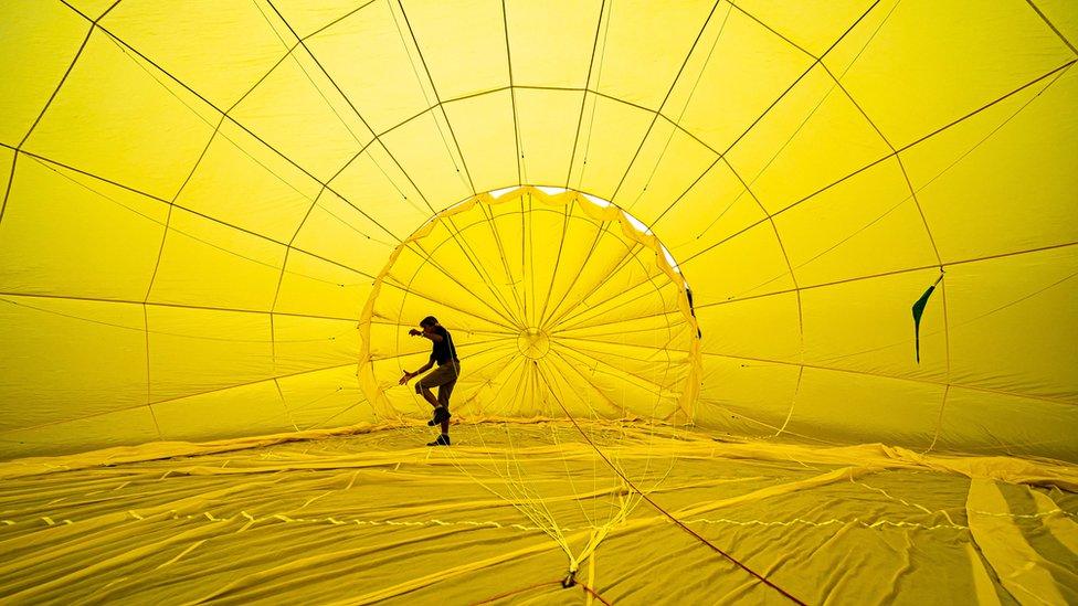 A man inside a hot air balloon preparing it for take off.