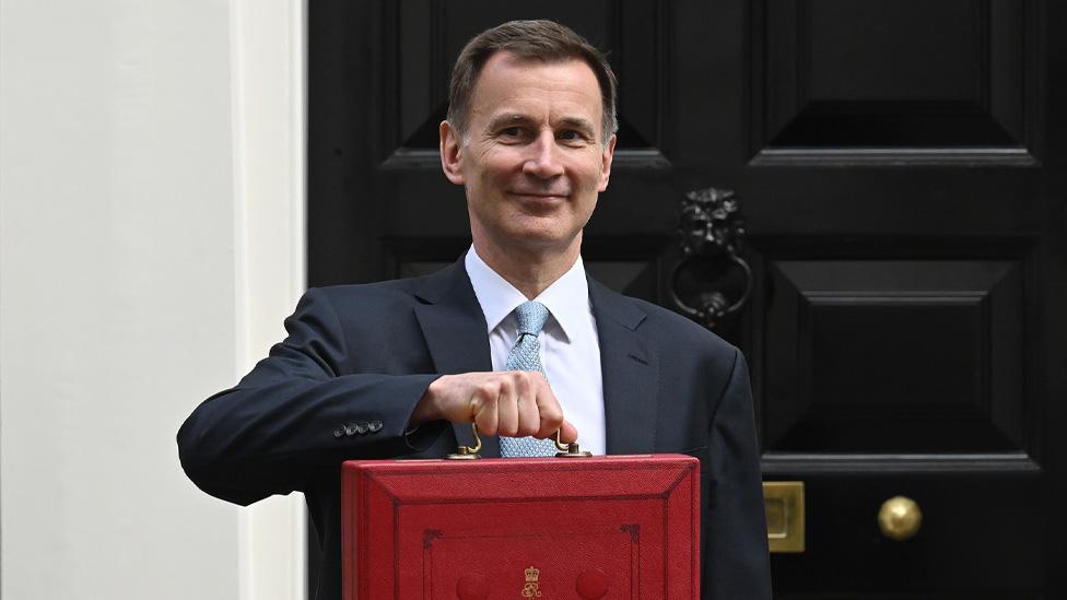 Chancellor Jeremy Hunt holds up his budget red box in front of the door of Number 11