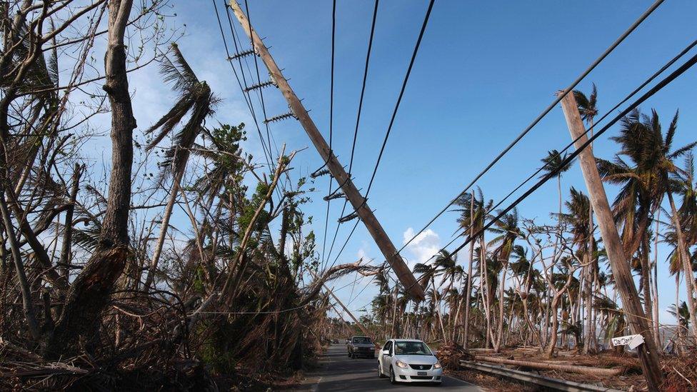 A car driving under a broken utility pole