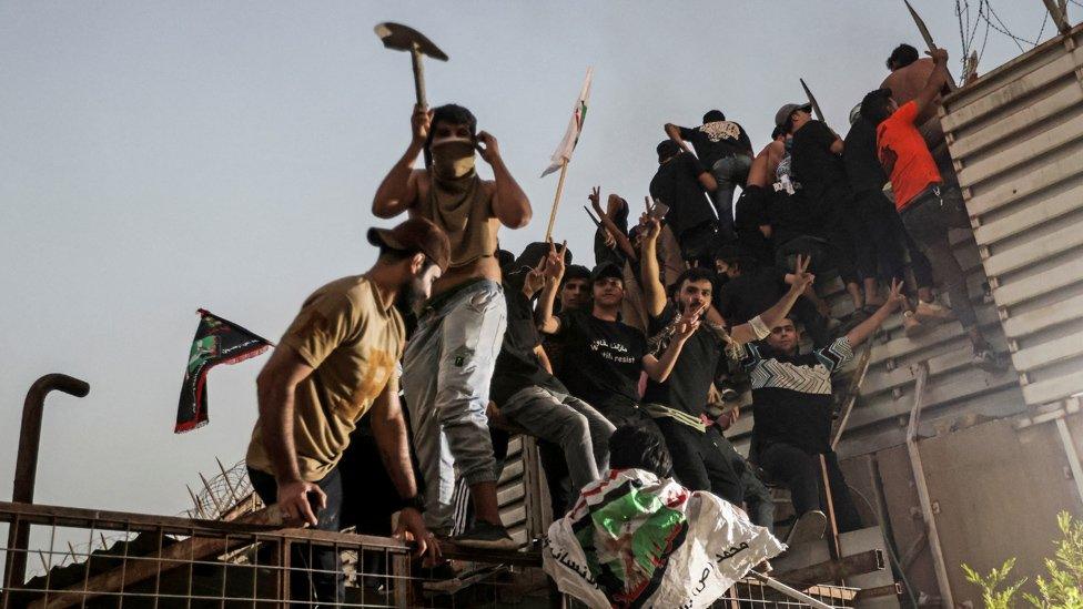 Protesters climb a fence as they gather near the Swedish embassy in Baghdad hours after the embassy was stormed and set on fire ahead of an expected Koran burning in Stockholm, in Baghdad, Iraq, July 20, 2023