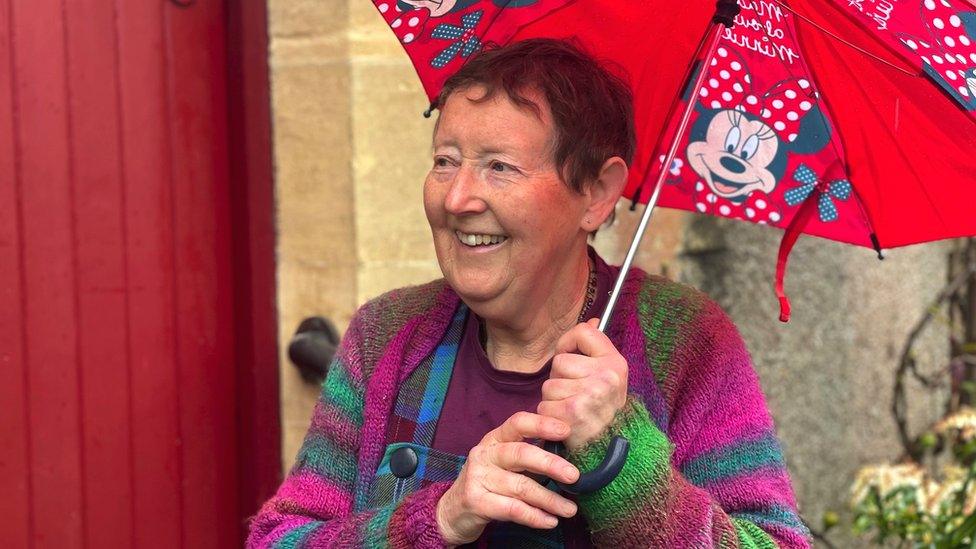 Annie standing in front of her front door with an umbrella