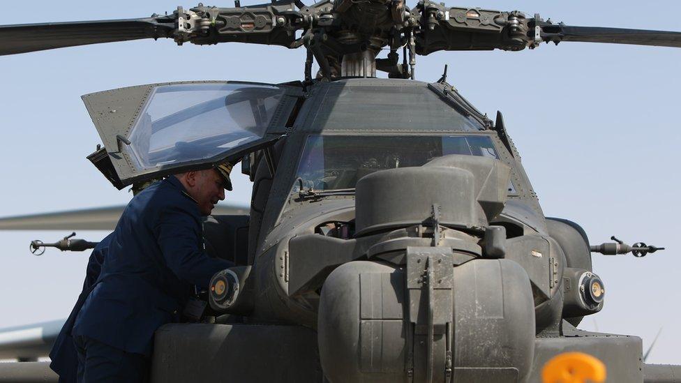 Tunisian officers look at a US Apache helicopter displayed at the Dubai Airshow on 8 Nov, 2015